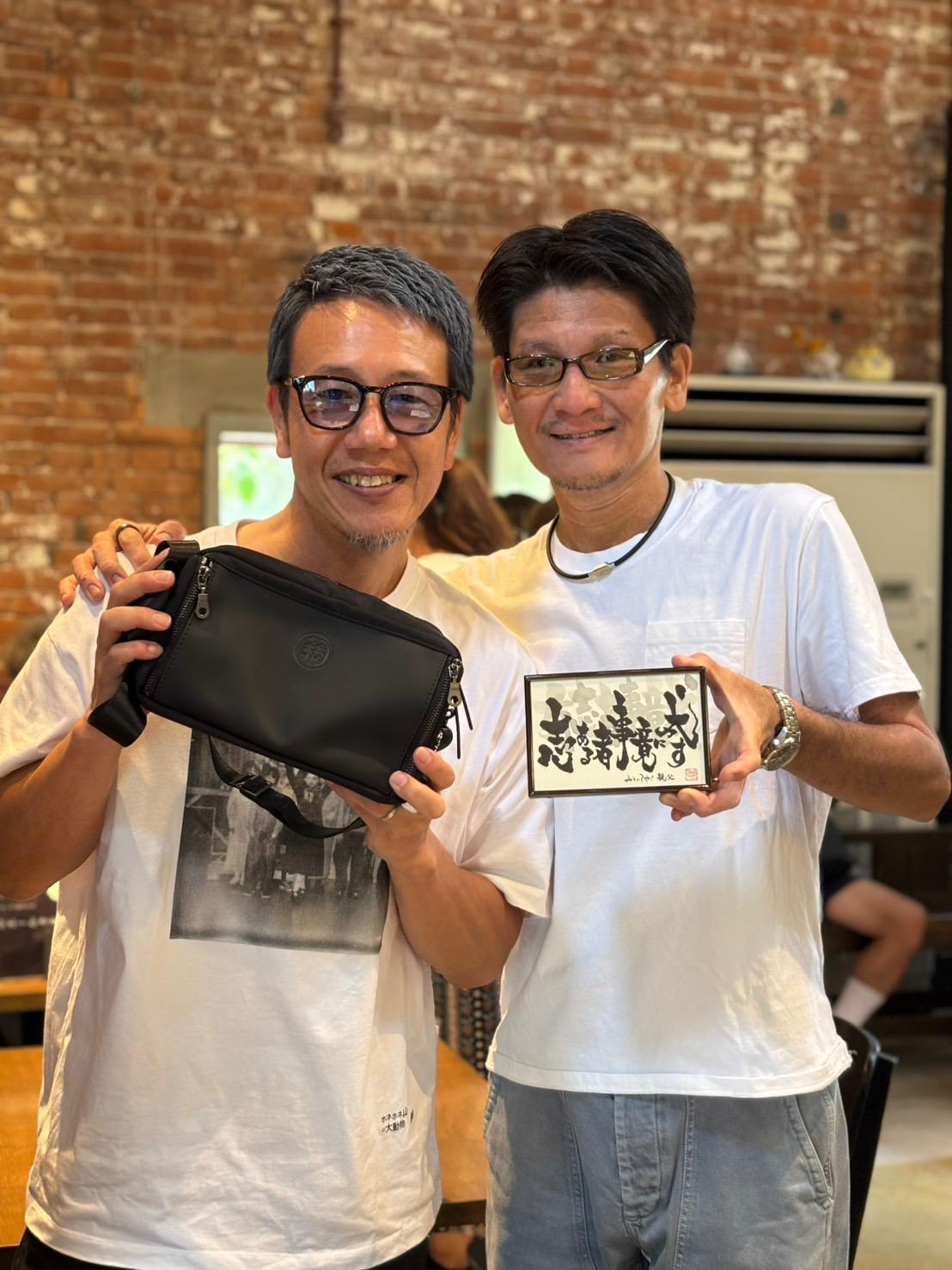 Two customers holding a black FLOUZ shoulder bag.
